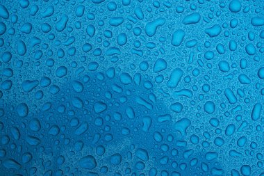 Mavi pürüzsüz bir yüzey üzerinde yağmur damlaları