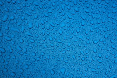 Mavi pürüzsüz bir yüzey üzerinde yağmur damlaları