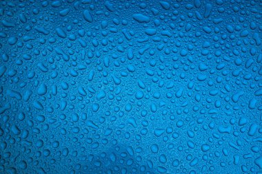 Mavi pürüzsüz bir yüzey üzerinde yağmur damlaları