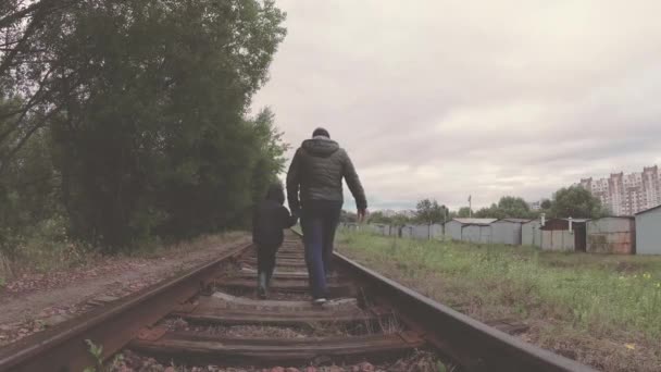 Das Kind mit dem Vater geht auf die Bahngleise. — Stockvideo