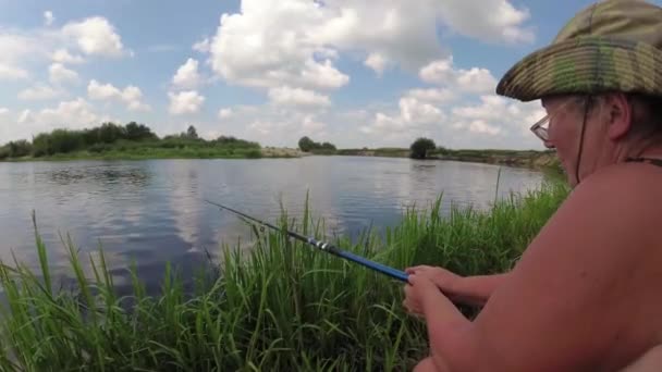 El pescador está pescando en el río con una caña de pescar . — Vídeos de Stock