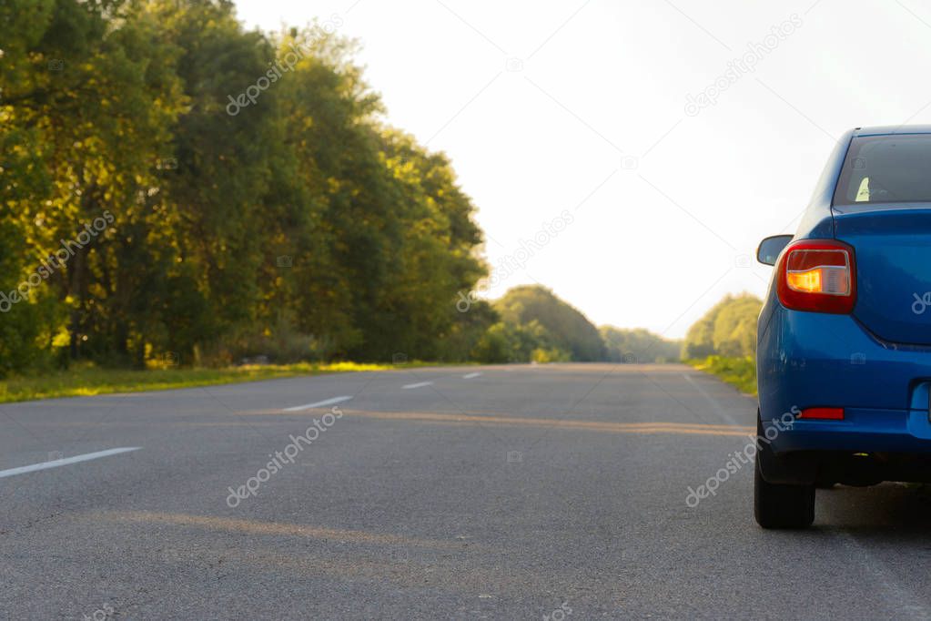 Car on asphalt road in summer evening