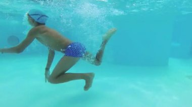 Genç su altında havuzunda yüzüyor.