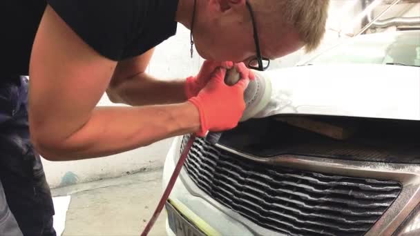 mladý muž opravuje auta v garáži.
