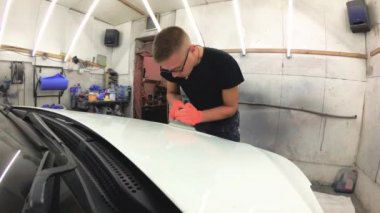 Genç adam araba garajda onarır.