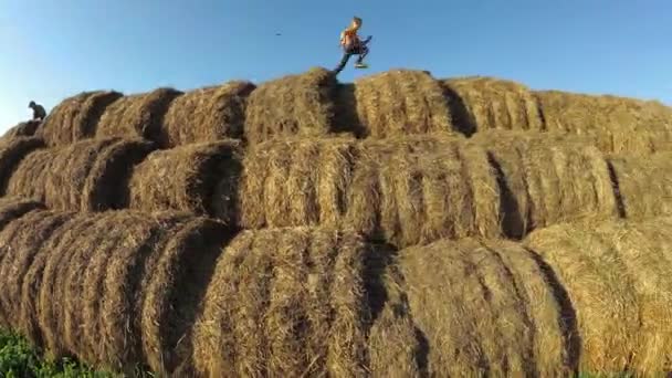 I bambini giocano in una pila di paglia . — Video Stock