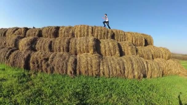 Los niños juegan en una pila de paja . — Vídeos de Stock