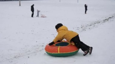 kış kar eğlenceli. Çocuk bir boru bir slayttan binmek..