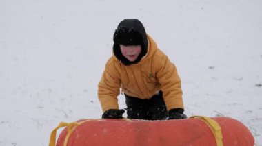 kış kar eğlenceli. Çocuk bir boru bir slayttan binmek..