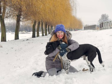 Güzel kız bir köpek karda sarılma