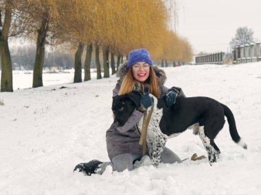 Güzel kız bir köpek karda sarılma