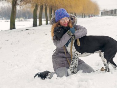 Güzel kız bir köpek karda sarılma