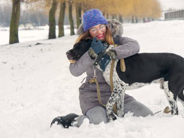 Güzel kız bir köpek karda sarılma