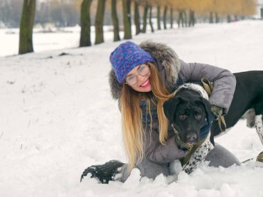 Güzel kız bir köpek karda sarılma
