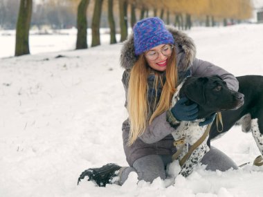 Güzel kız bir köpek karda sarılma