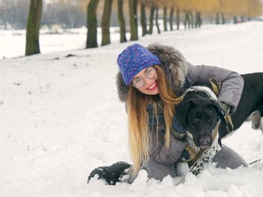 Güzel kız bir köpek karda sarılma