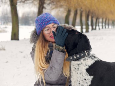 Güzel kız bir köpek karda sarılma