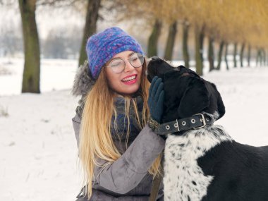 Güzel kız bir köpek karda sarılma