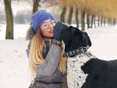 Güzel kız bir köpek karda sarılma