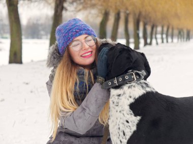 Güzel kız bir köpek karda sarılma