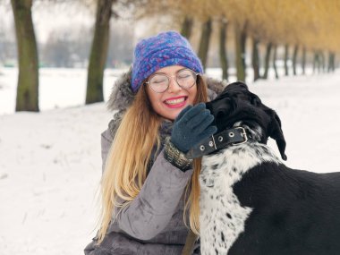 Güzel kız bir köpek karda sarılma