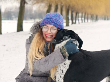 Güzel kız bir köpek karda sarılma