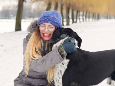 Güzel kız bir köpek karda sarılma