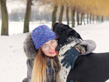 Güzel kız bir köpek karda sarılma