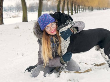 Güzel kız bir köpek karda sarılma