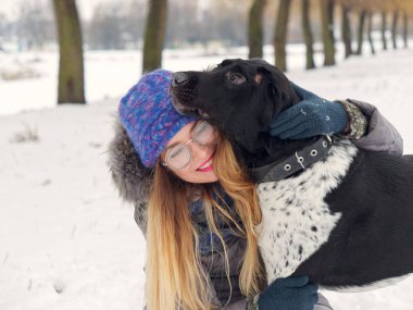 Güzel kız bir köpek karda sarılma