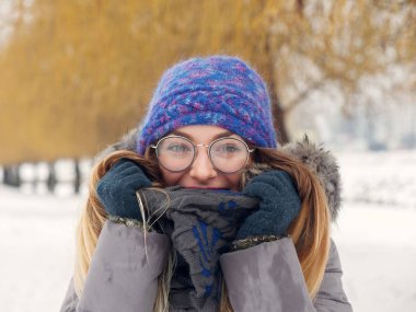 İçinde belgili tanımlık soğuk mavi bir şapka ve gözlük yuvarlak güzel mutlu kız