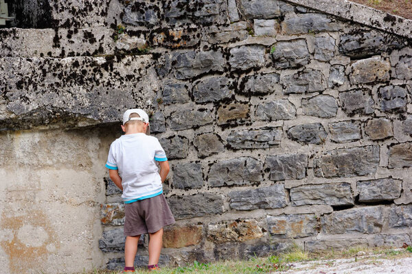boy pissing on a stone wall in the city
