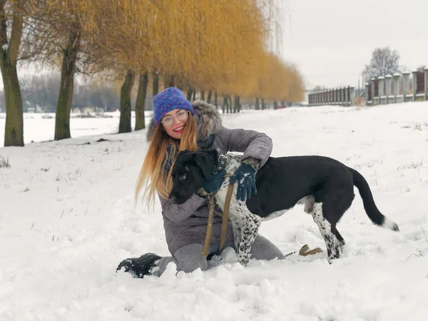 Güzel kız bir köpek karda sarılma