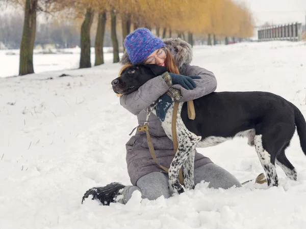 Güzel kız bir köpek karda sarılma