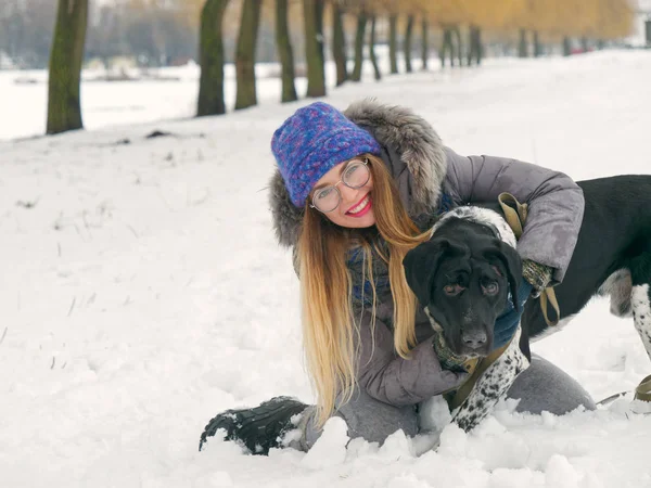 Güzel kız bir köpek karda sarılma