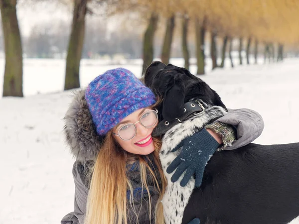 Güzel kız bir köpek karda sarılma