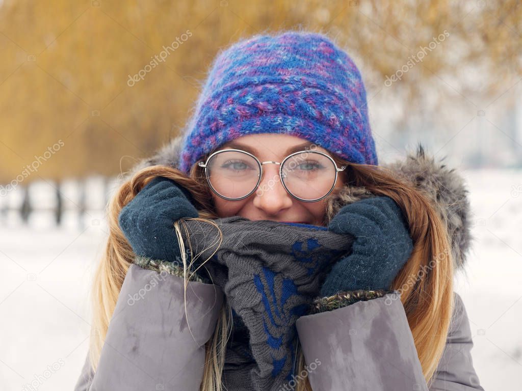 Beautiful happy girl in the cold in a blue hat and round glasses