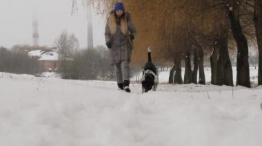 Güzel neşeli kız köpek işaretçi karda yürüyüş.