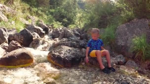 孩子坐在大自然岩石上的溪边 — 图库视频影像