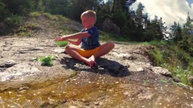 doğada buzlu brook tarafından çocuk oturur.