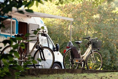 Barcis, Pordenone, Italy a picturesque place camping tourist parking by cars and bicycles clipart
