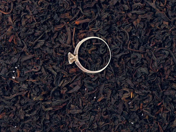 background of black tea leaves. precious ring. decorations