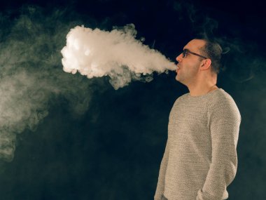 Genç adam elektronik sigara içiyor.