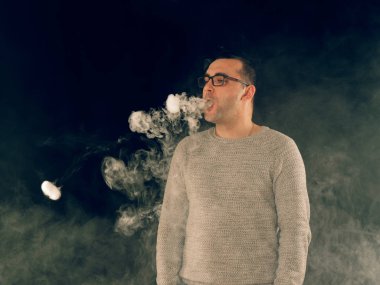 Genç adam elektronik sigara içiyor.