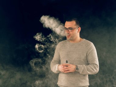 Genç adam elektronik sigara içiyor.