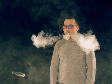 Genç adam elektronik sigara içiyor.