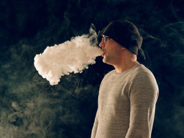 Genç adam elektronik sigara içiyor.