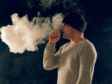 Genç adam elektronik sigara içiyor.