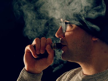 Genç adam elektronik sigara içiyor.