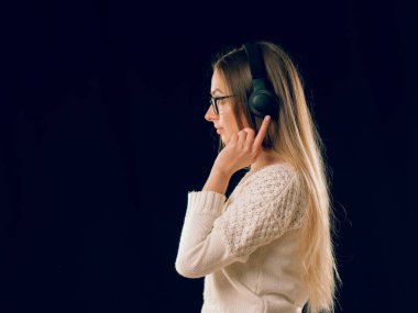 Güzel zevk genç kadın koyu siyah arka plan üzerine kablosuz kulaklık müzik dinleme